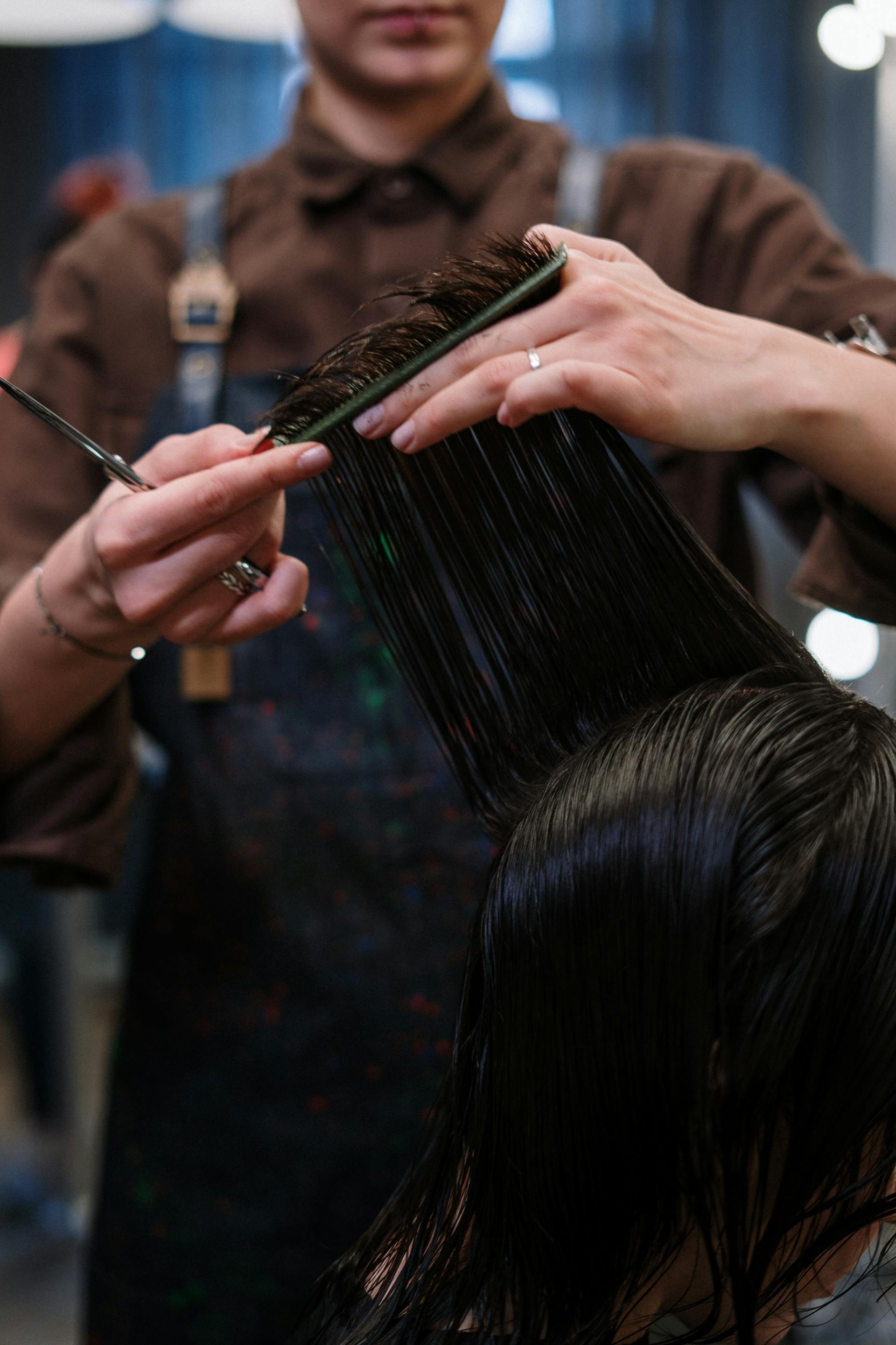 Close-up of a hairstylist using scissors to cut wet hair in a professional salon